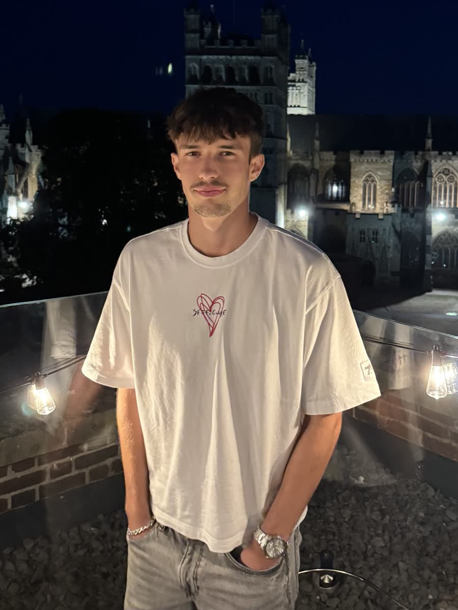 Charlie, founder of Orla Media, in Exeter at night with the cathedral behind him.